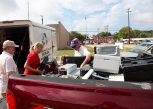 Keep Nacogdoches Beautiful directors (left to right) Mike Keller, Cheryl Bartlett and Mark Holl unload several recycled technology items from a participant's truck.