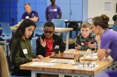 Stephen F. Austin State University alumna Rachel Payne helps students play a game based on chess, titled Game of Amazons and designed to teach how rule changes impact winning strategies. The students participated in SFA’s Julia Robinson Mathematics Festival.