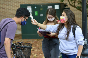 SFA voice students Kayla Luptak, senior from Bullard, and Gisselle Gonzalez, senior from Houston, check the temperature of Antony Pham, Houston sophomore, prior to A Cappella Choir rehearsals.