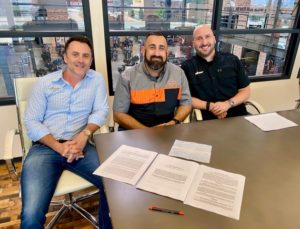 Adam Smith, Calculated Risk owner/president; Saul Elizondo, GM and new part owner of Lumberjack Harley-Davidson; Neil Noble, Calculated Risk partner; at signing.