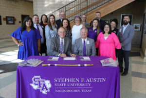 Stephen F. Austin State University's interim president Dr. Steve Westbrook and Hays Consolidated Independent School District Superintendent Dr. Eric Wright, both seated, sign an agreement naming Hays CISD as a partner in the university's Distinguished High School Program.